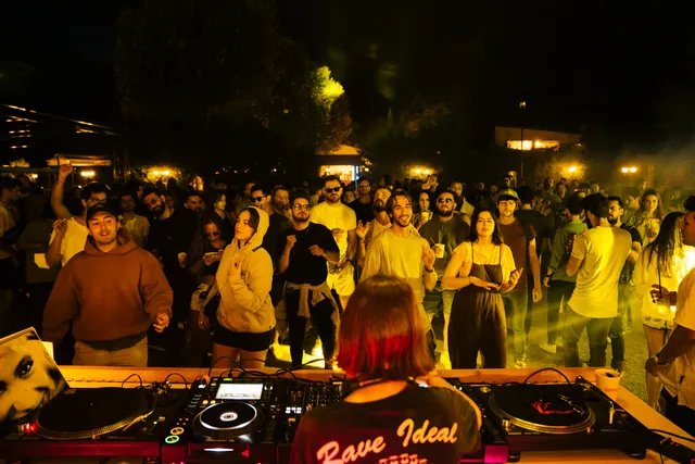 The yellow-lit crowd seen from behind the booth