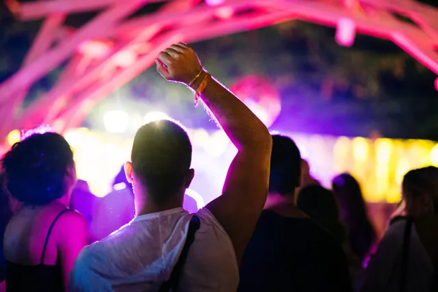 Arms raised beneath purple lights
