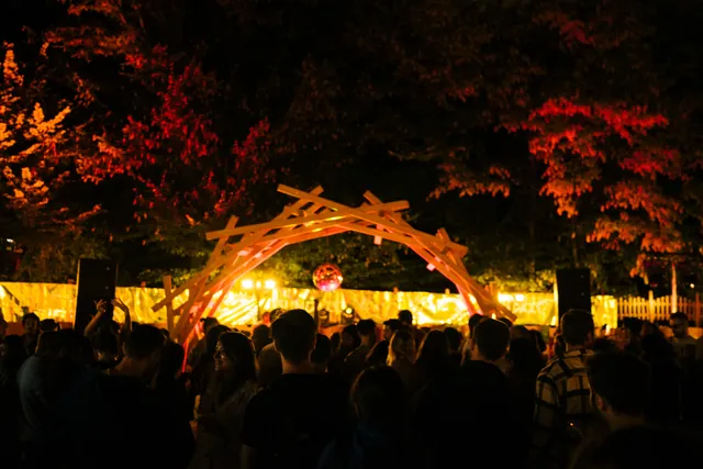 The illuminated booth seen from the garden at night