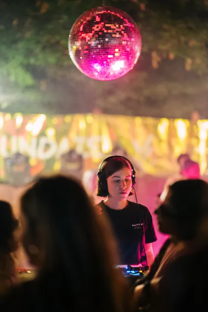 The DJ booth beneath the mirror ball, seen through the crowd
